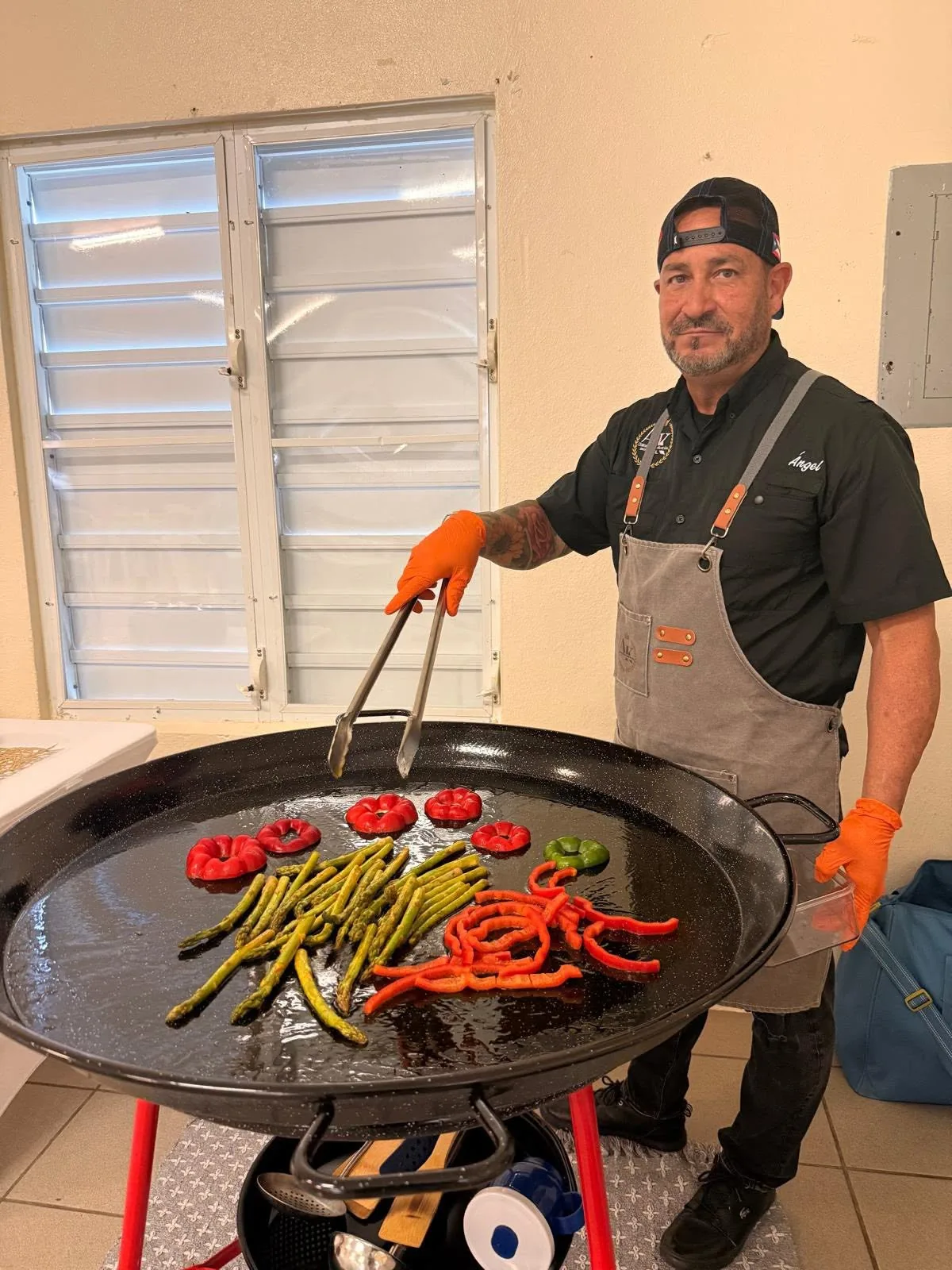 El chef Ángel colocando pimientos, espárragos y chorizo sobre la paellera antes de empezar
