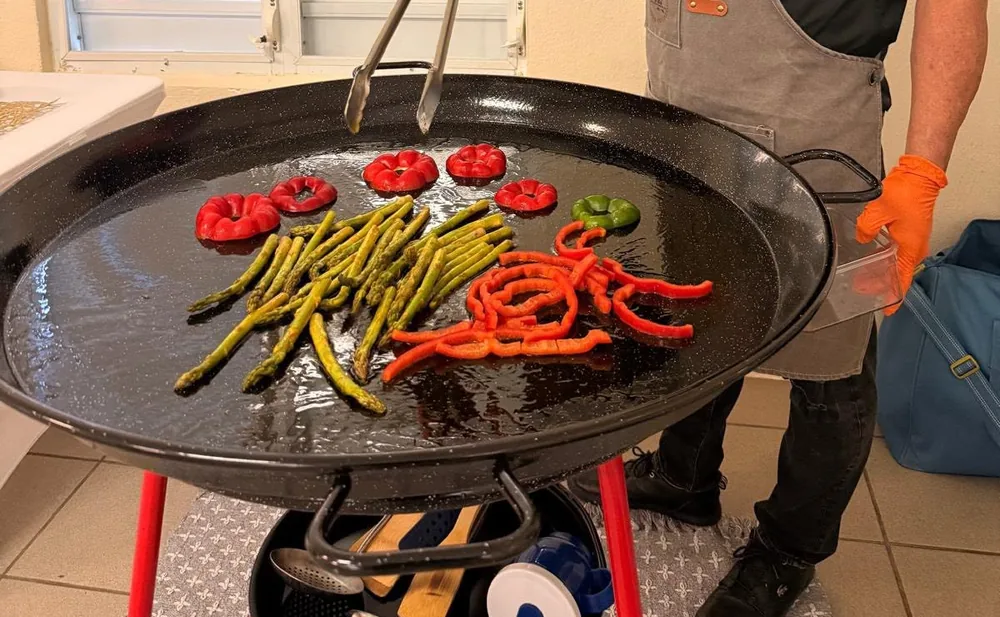 Pimientos, espárragos y chorizo colocados sobre la paellera negra