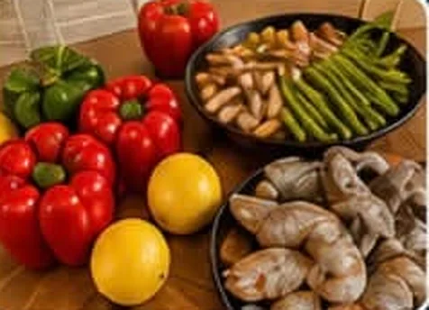 Pimientos, limones, espárragos y camarones frescos antes de empezar la paella