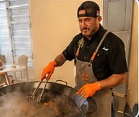 El chef Ángel cocinando sobre la paellera con el vapor subiendo